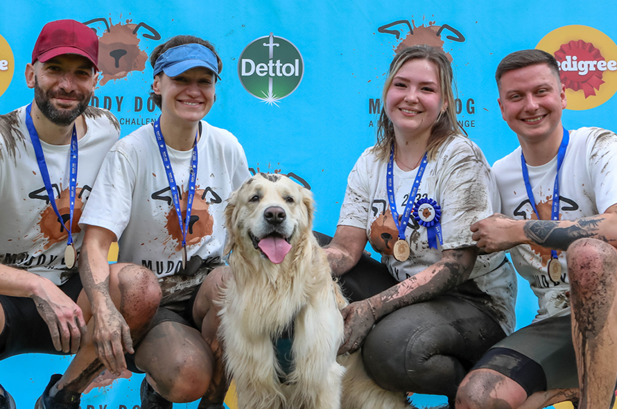 People posing in front of a sign with a dog