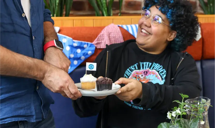 A person handing cake to another person